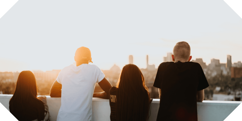 Four friends standing watching the sunset together, enjoying each other's friendship.